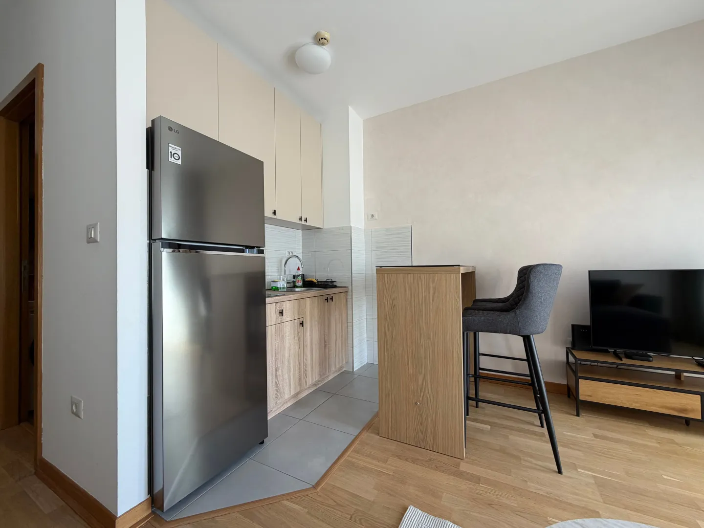 Compact kitchen with a refrigerator and a bar counter integrated into the living area.