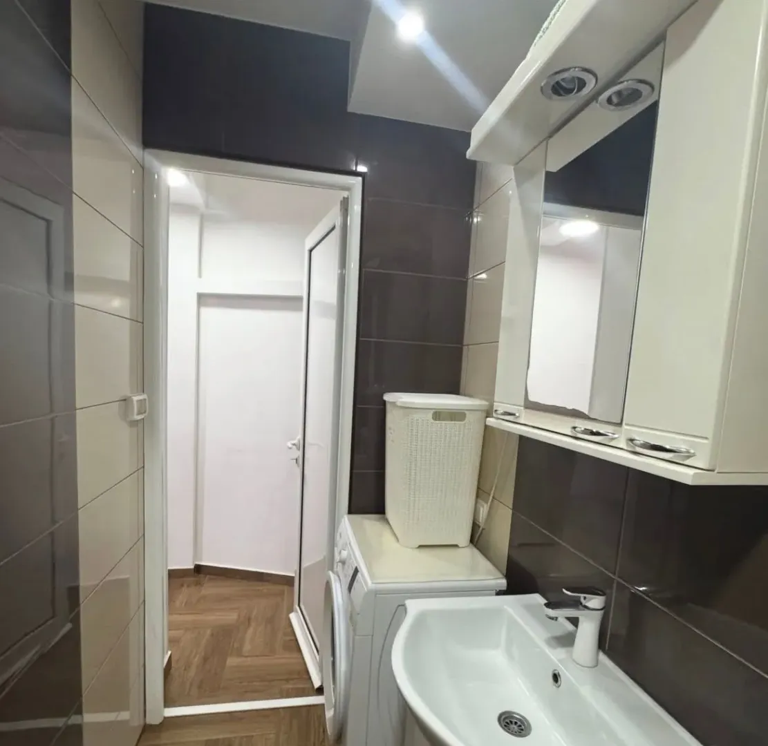 Small bathroom with a sink, mirrored cabinet, and washing machine.