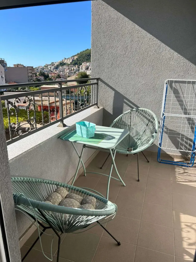 Furnished balcony with a table, chairs, and city view.