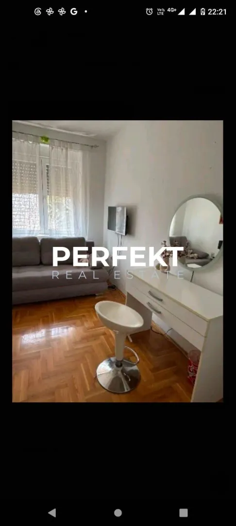 Nameštena spavaća soba sa krevetom, radnim stolom i ogledalom.