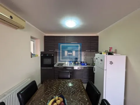 Kuhinja sa tamnim elementima i trpezarijskim stolom u sredini. - image 30