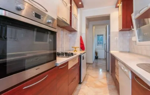 Narrow equipped kitchen with wooden elements and a built-in oven. - image 2