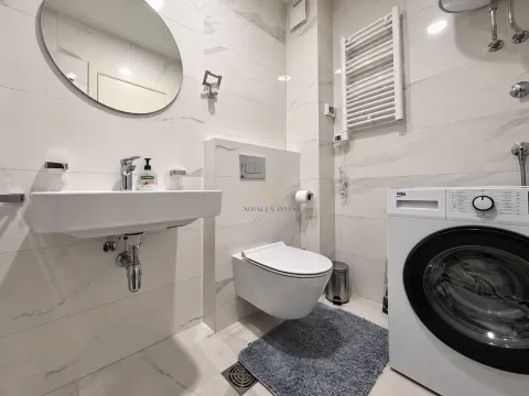 Modernly equipped bathroom with a washbasin, toilet, and washing machine. - image 9