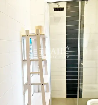 View of a modern bathroom with a glass shower cabin and a wooden shelf. - image 12