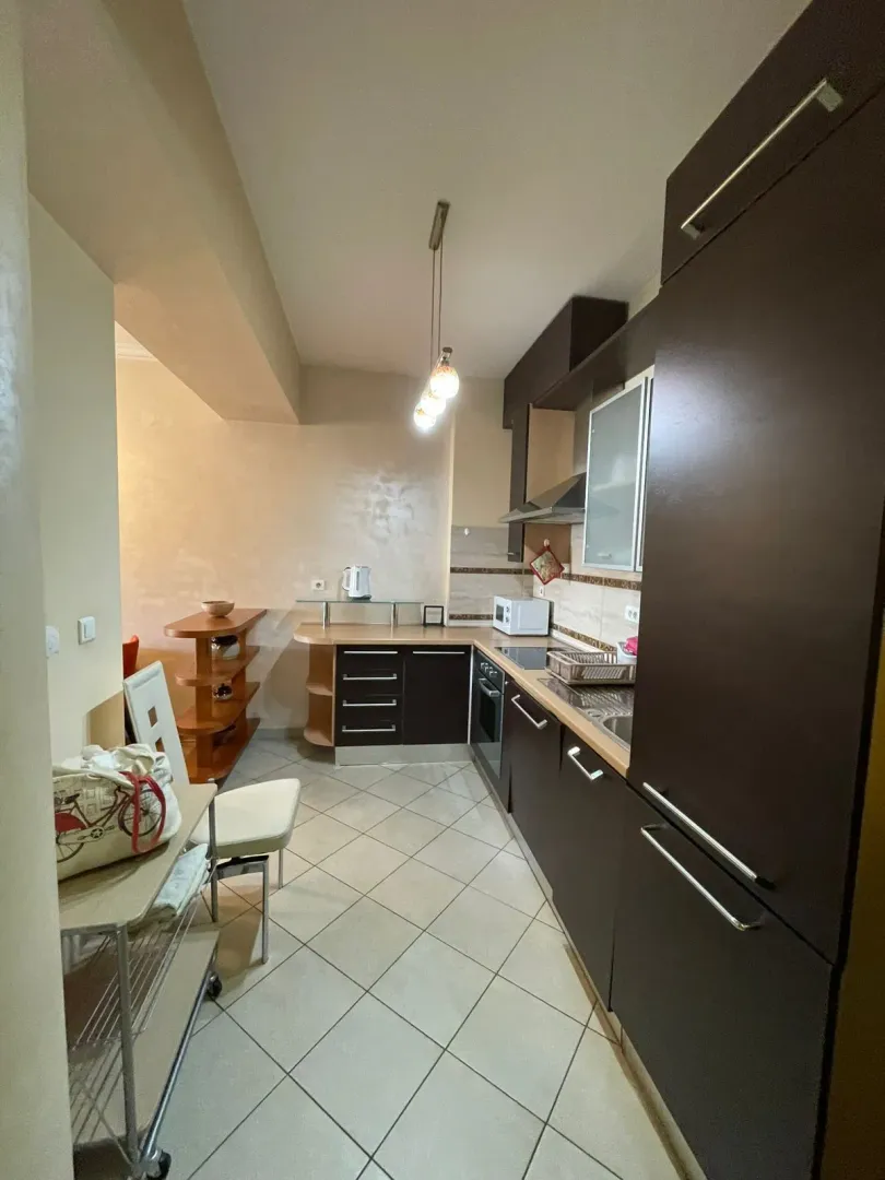 Manja kuhinja sa tamnim elementima i trpezarijskim dijelom u produžetku.