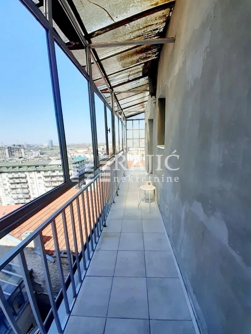 Long enclosed balcony with a city view.
