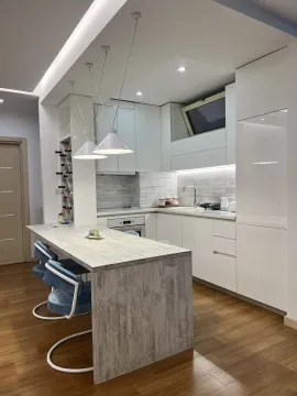 Moderna kuhinja sa bijelim elementima, šankom i trpezarijskim stolicama. - image 3