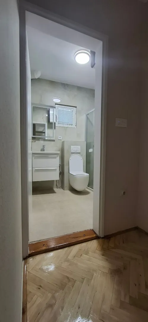 Pogled iz hodnika na uređeno kupatilo sa sanitarijama.