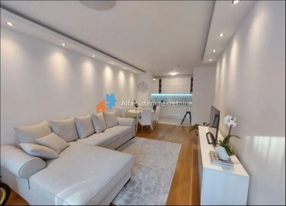 Living room with sofa, TV unit and dining area in the background.
