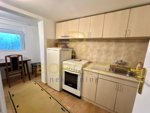 Manja kuhinja sa svetlim drvenim elementima i trpezarijskim delom u pozadini. - image 5