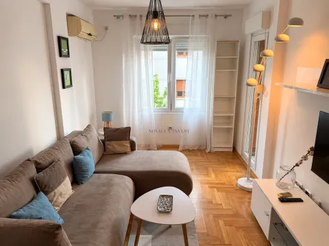 Small living room with a corner sofa, TV, and parquet flooring. - image 2