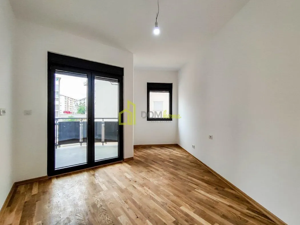 Empty room with wooden flooring and access to the terrace.