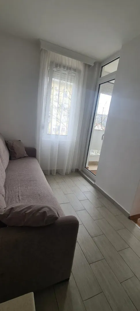 Svijetla prostorija sa kaučem pored balkonskih vrata.
