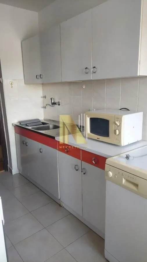 View of a small kitchen with light-colored cabinets and appliances.