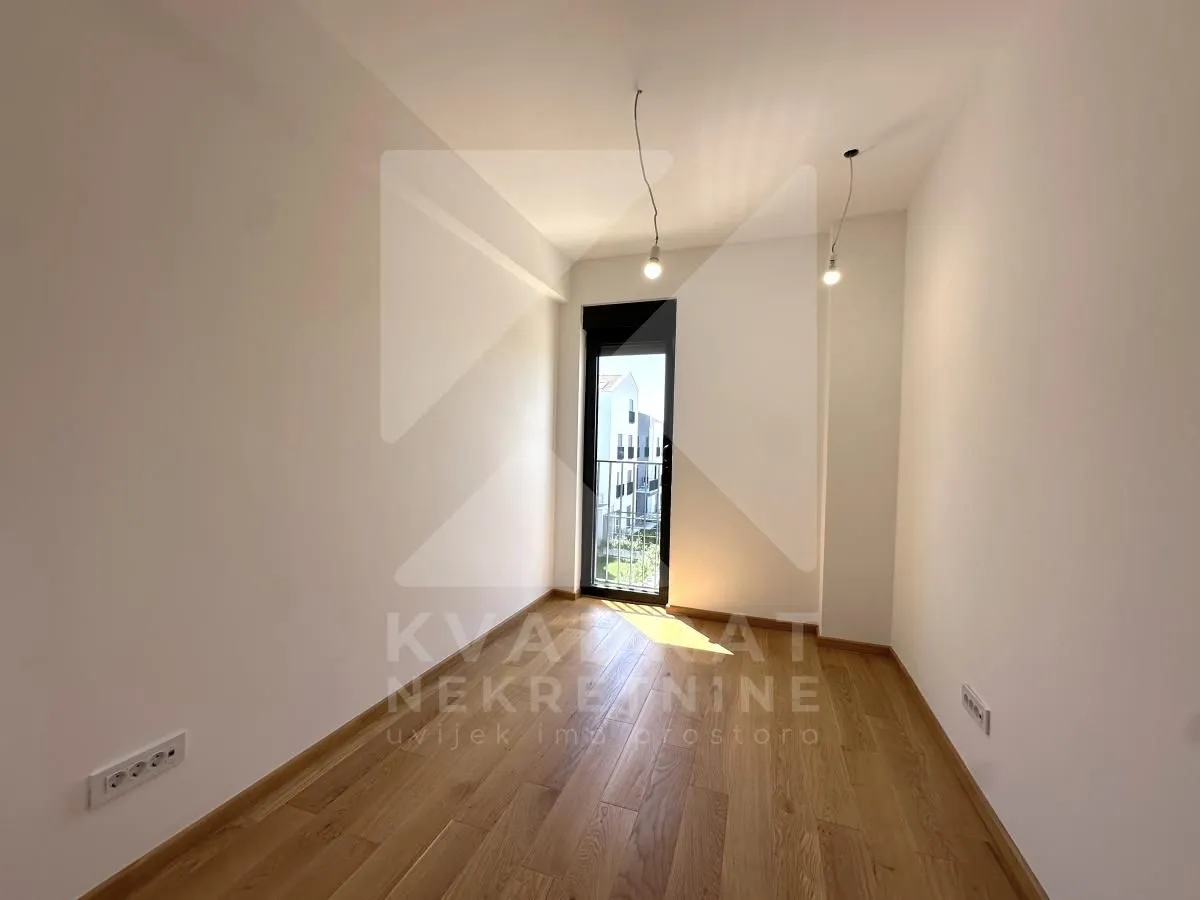 Empty room with wooden flooring and balcony access.