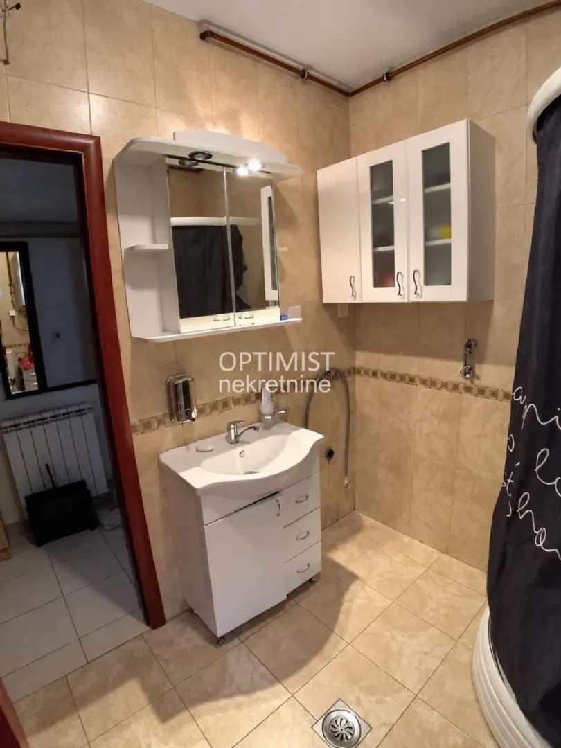 Kupatilo sa umivaonikom, ogledalom i belim visećim elementima.