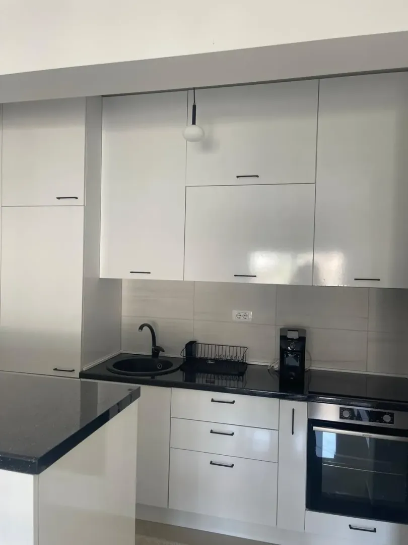 Modern white kitchen with black elements and built-in appliances.