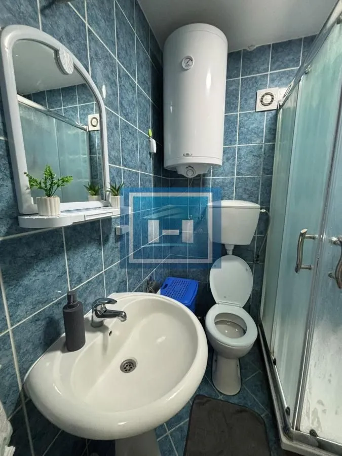Manje kupatilo sa tuš-kabinom, umivaonikom, WC šoljom i bojlerom.