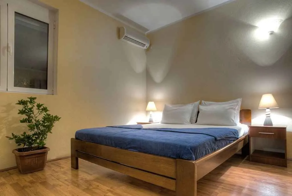 Svijetla spavaća soba sa bračnim krevetom i noćnim stočićima.