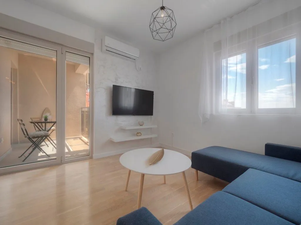 Living room with a corner sofa, TV, and access to the terrace.