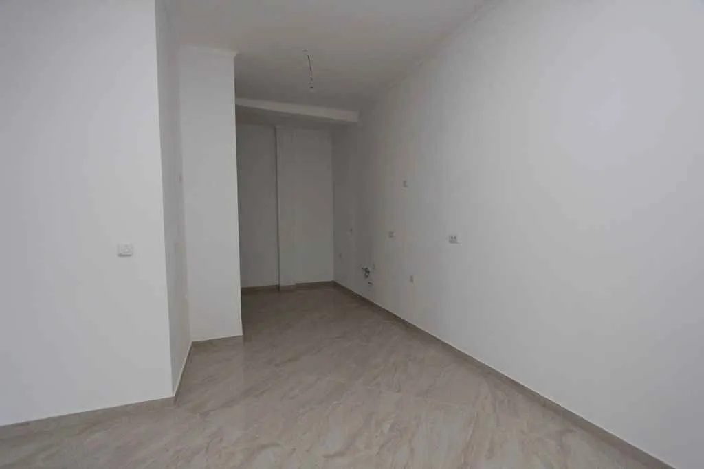 Prazna, neopremljena prostorija sa svijetlim pločicama i bijelim zidovima.