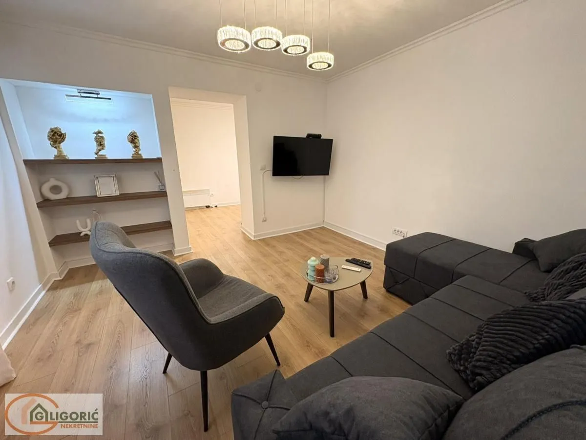 Living room with a sectional sofa, armchair, coffee table, and a wall-mounted TV.