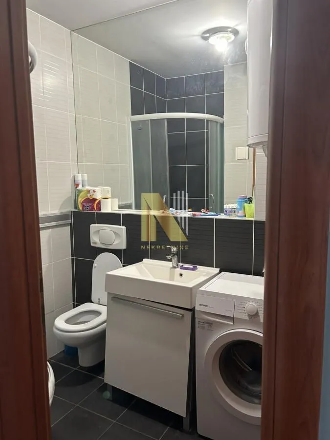 Kupatilo opremljeno sanitarijama, tuš kabinom i veš mašinom.