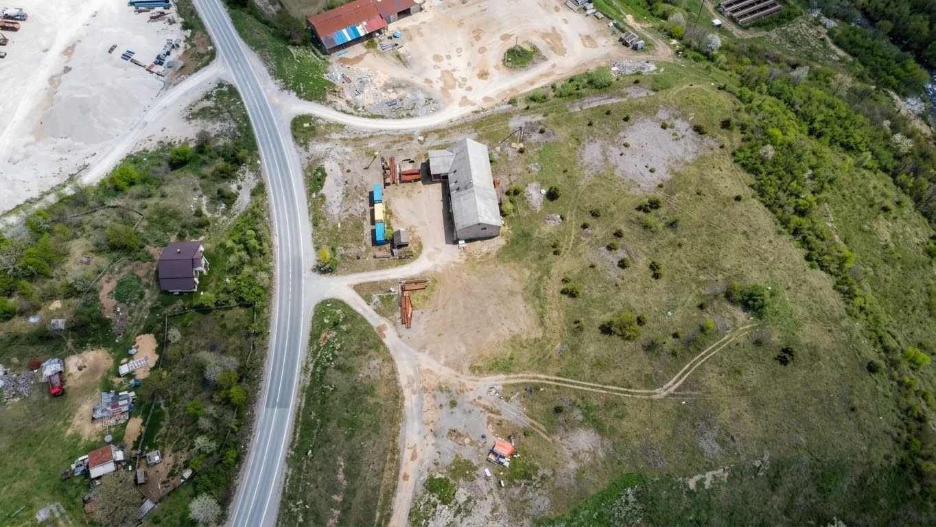 Pogled iz vazduha na imanje sa objektima i pristupnim putem.