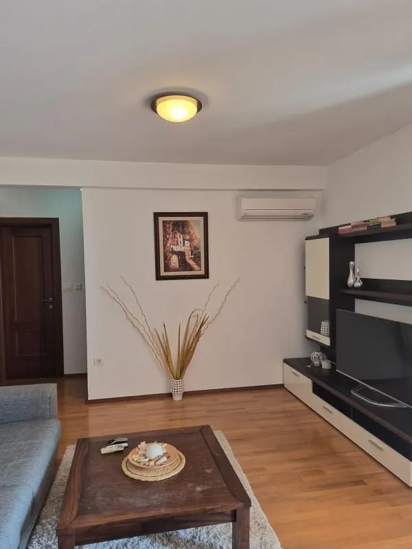 Dnevna soba sa garniturom, televizorom i drvenim stočićem.