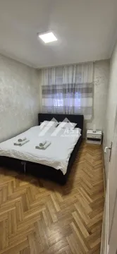 Manja spavaća soba sa bračnim krevetom, parketom i prozorom sa zavesama. - image 6