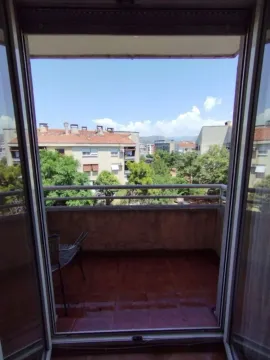 View from the balcony overlooking surrounding buildings and greenery. - image 7