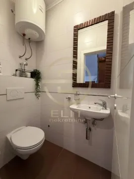Kompaktno kupatilo sa belim pločicama, umivaonikom, WC šoljom i ogledalom. - image 35