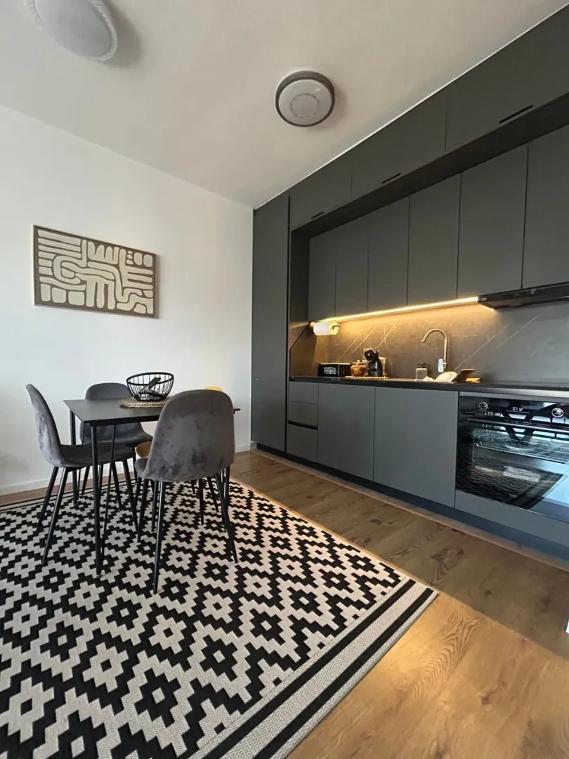 Modern kitchen with a dining area and dark cabinetry.