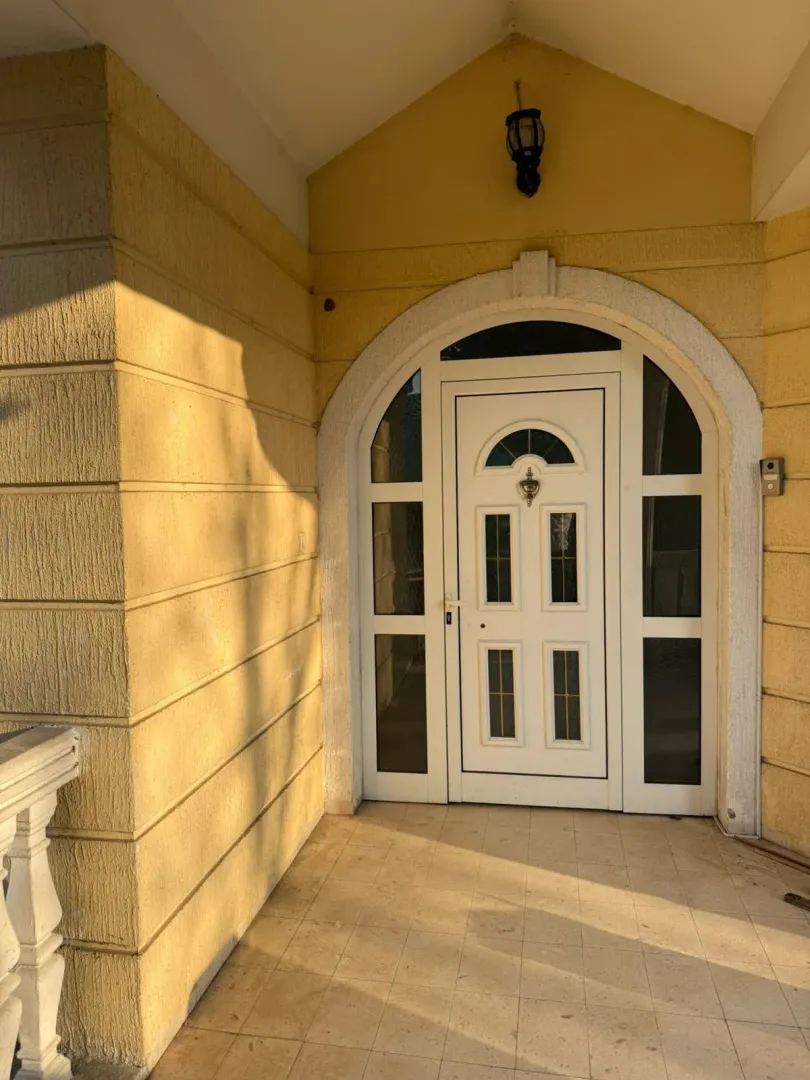 An entrance door with an arched frame on a yellow house facade.