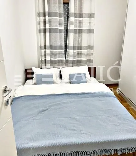 Bedroom with a double bed, a white wardrobe, and a window with curtains.