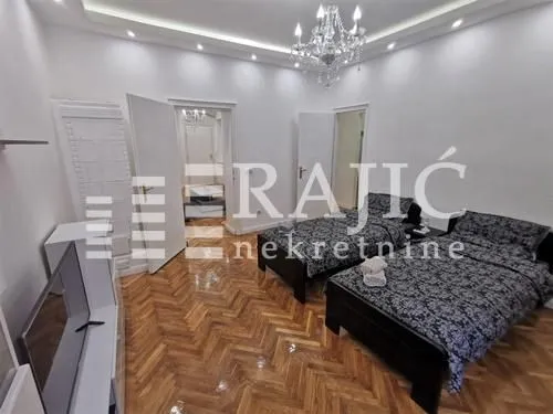 Bedroom with two beds and parquet flooring.
