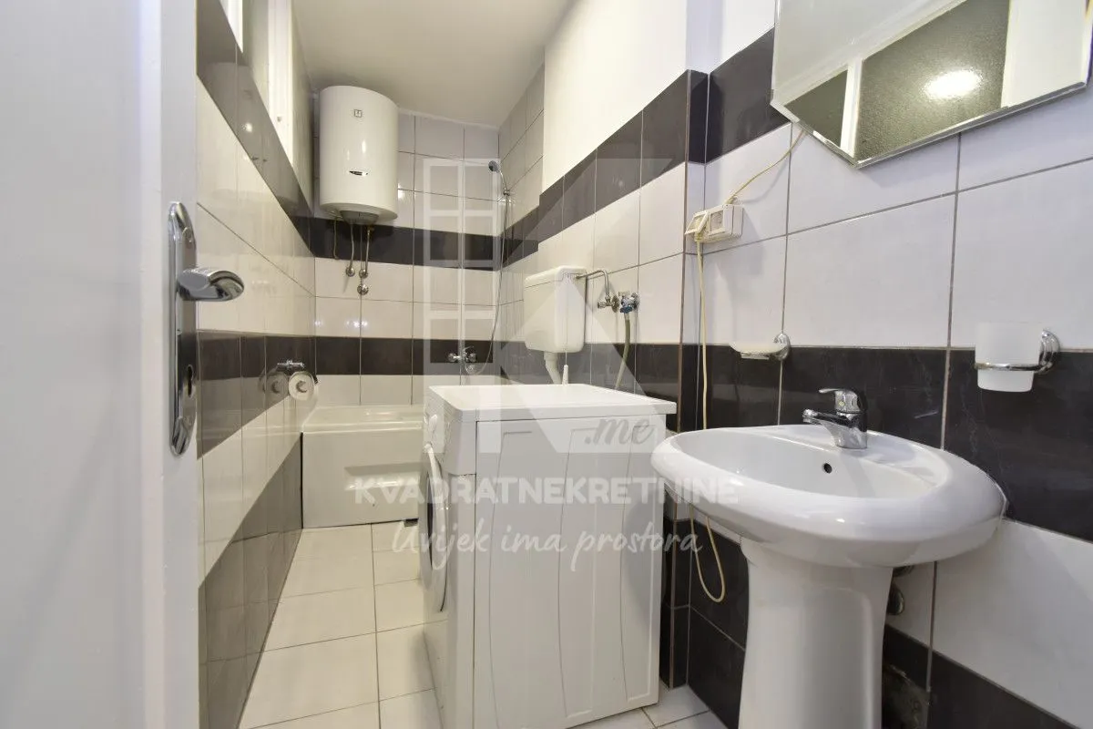 Small bathroom with a sink, washing machine, and bathtub.