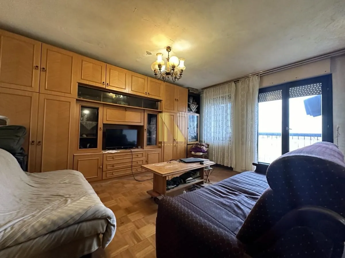 Dnevna soba sa garniturom, drvenim nameštajem i izlazom na terasu.
