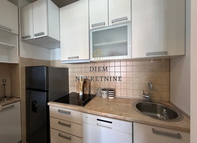 Smaller kitchen with white cabinets, built-in cooktop, and refrigerator.
