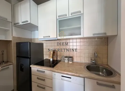 Smaller kitchen with white cabinets, built-in cooktop, and refrigerator. - image 6