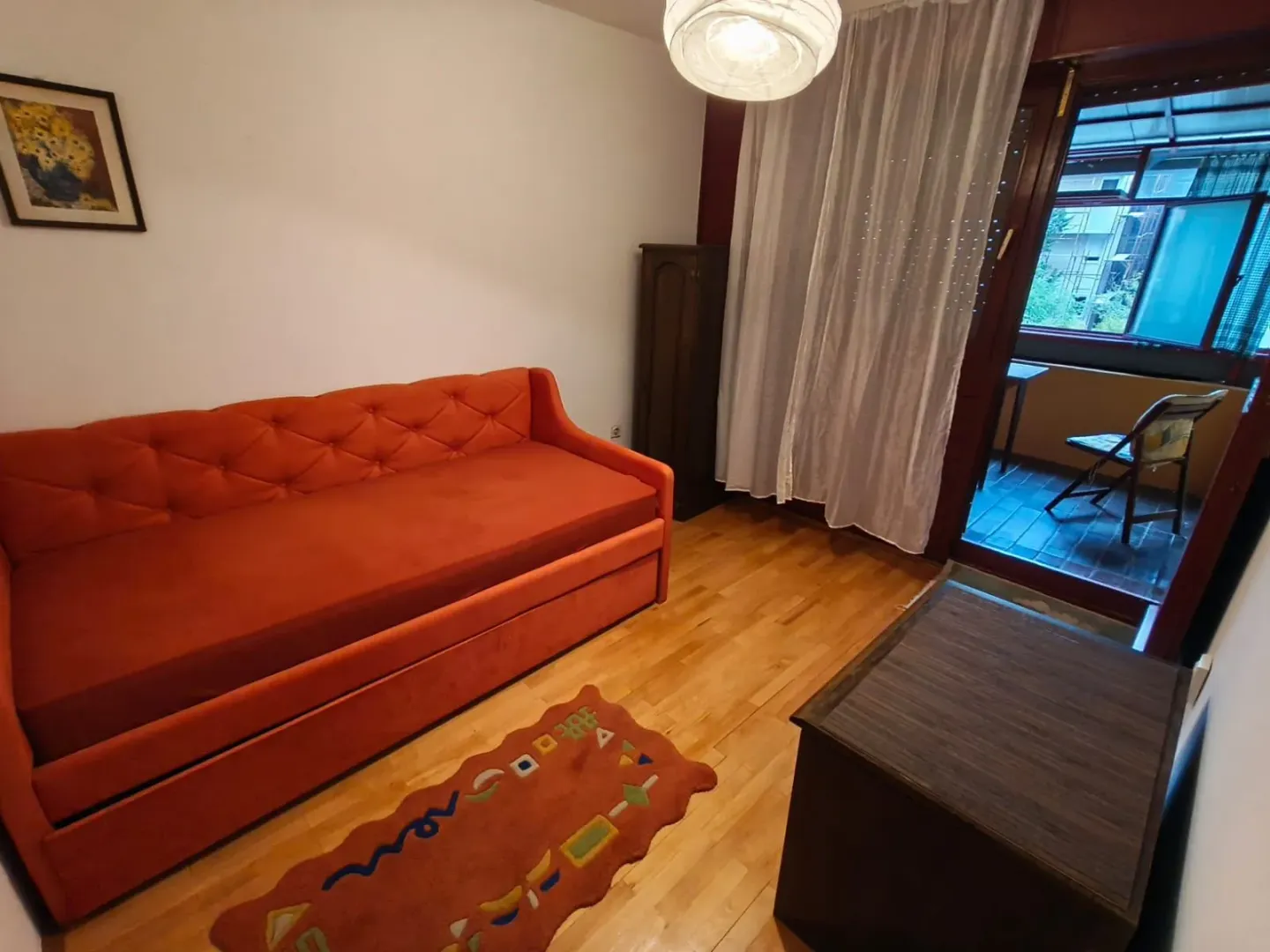 Dnevna soba sa narandžastom sofom i izlazom na terasu.