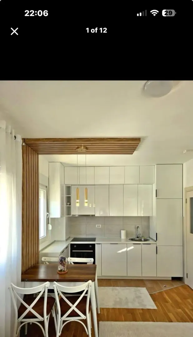 Modern kitchen with white cabinetry and a wooden dining set.