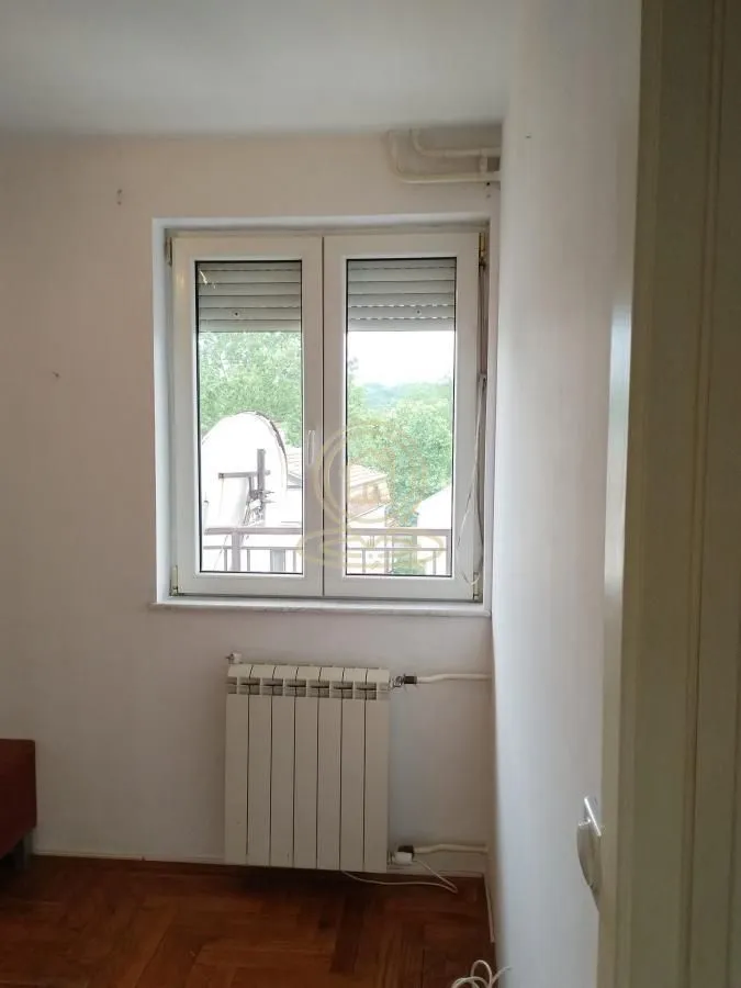 Pogled na prozor i radijator u sobi sa parketom.
