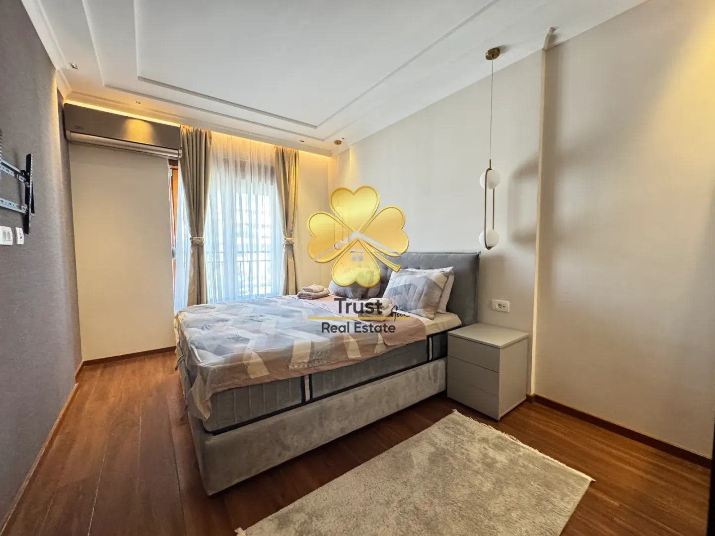A furnished bedroom with a double bed and a window with curtains.