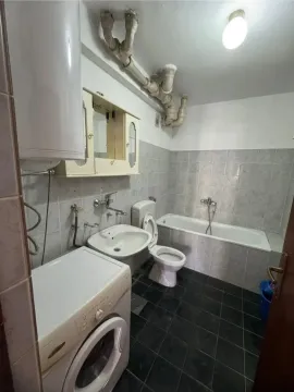 Bathroom equipped with a bathtub, sink, toilet, and washing machine. - image 4