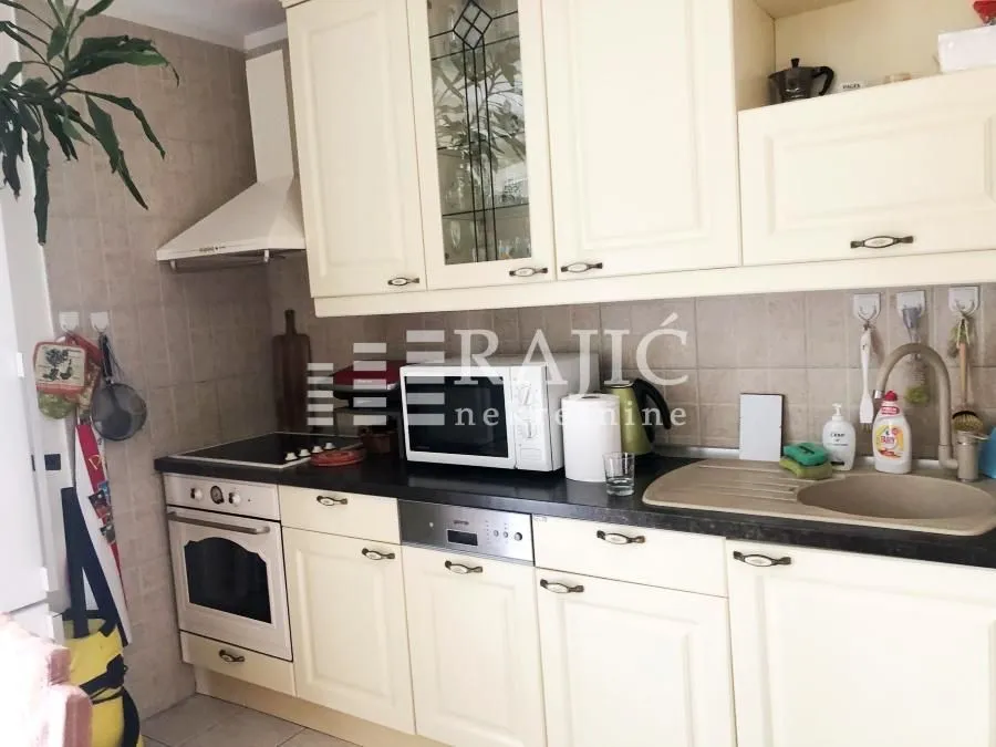 Equipped kitchen with white cabinets and built-in appliances.