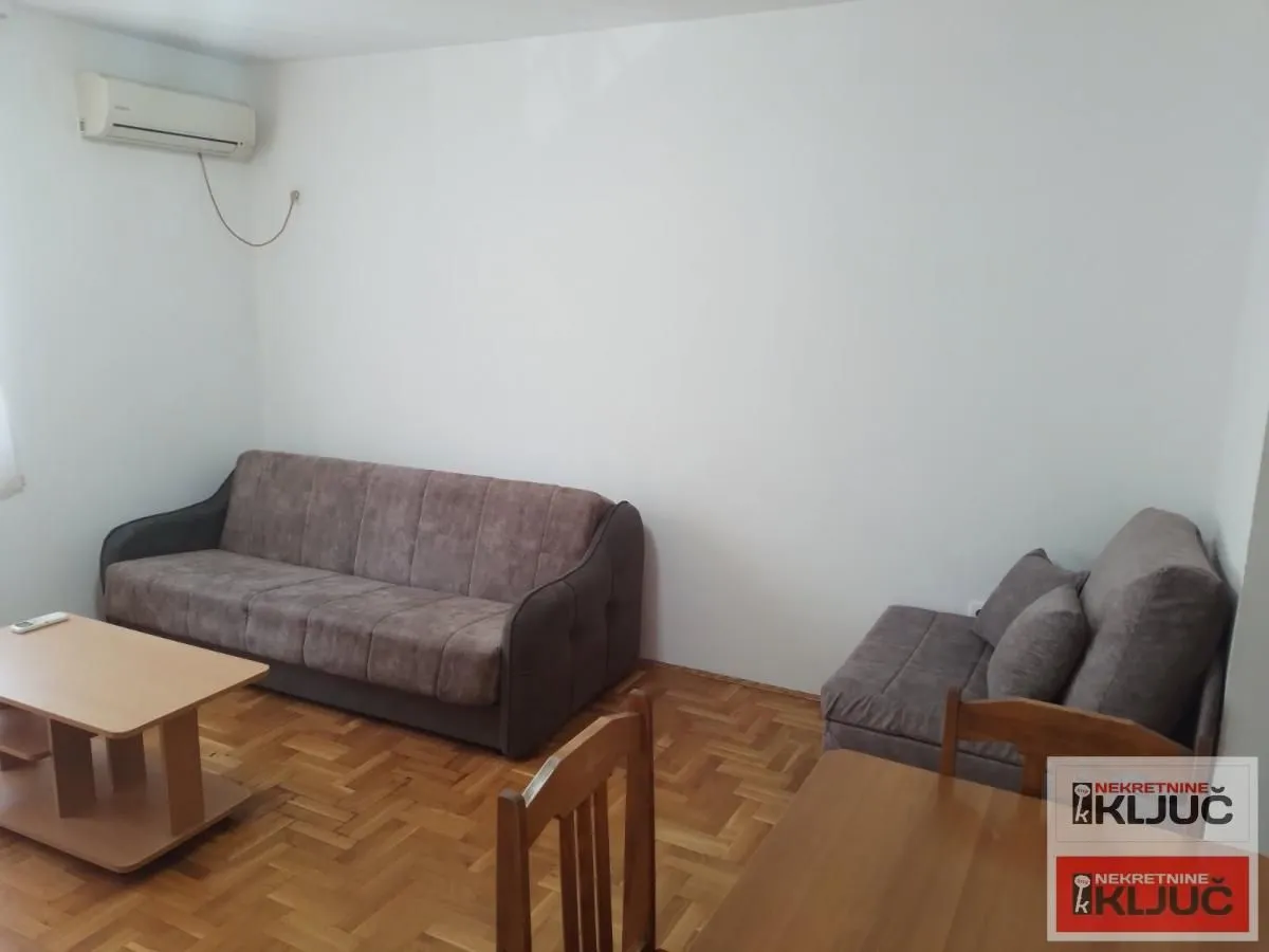 Dnevna soba sa garniturom za sedenje i klima uređajem.