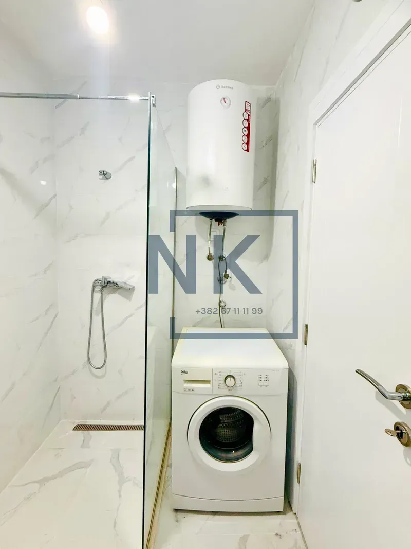Bathroom with a shower cabin, washing machine, and water heater.