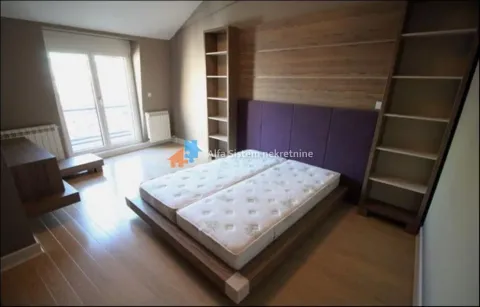 Furnished bedroom with a double bed, wooden panels and shelving units. - image 11