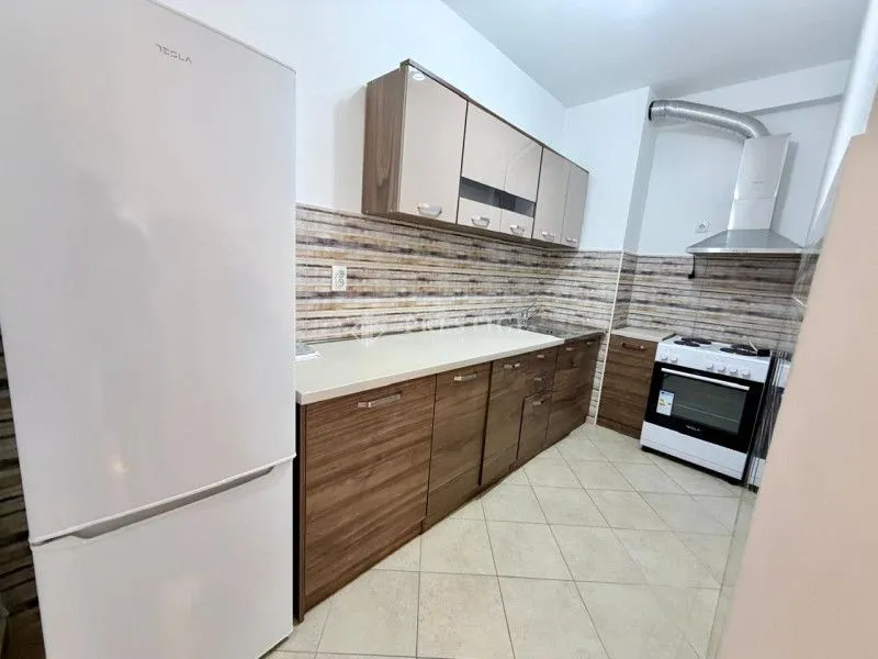 Moderna kuhinja sa drvenim elementima, bijelim frižiderom i šporetom.